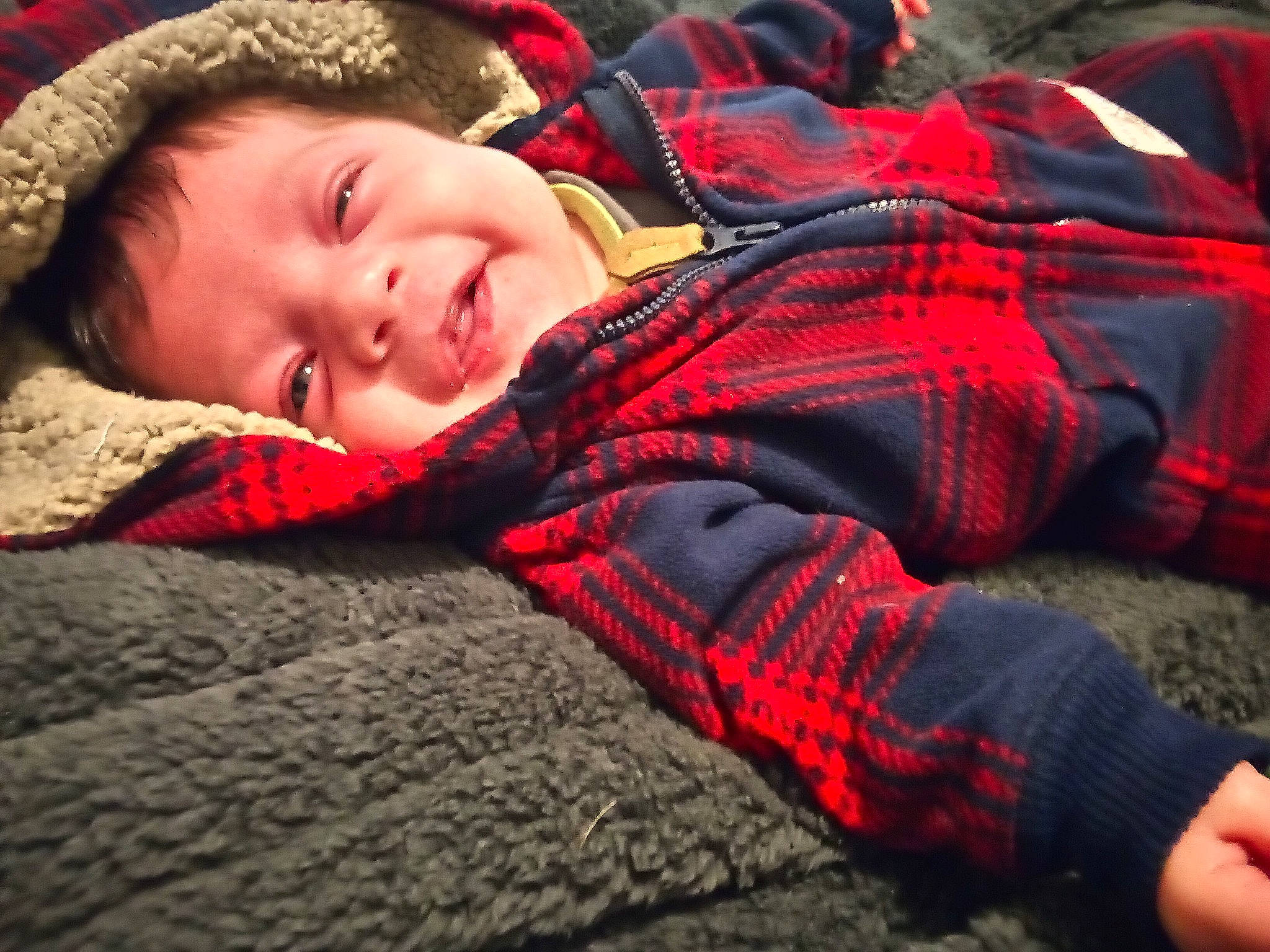 Sawyer is registered to the contest to win money with this photo: bedtime, carmine, child, comfort, flooring, fur, human_leg, linens, orange, pattern, person, plaid, red, sitting, smile, tartan, textile, toddler, wood, wool