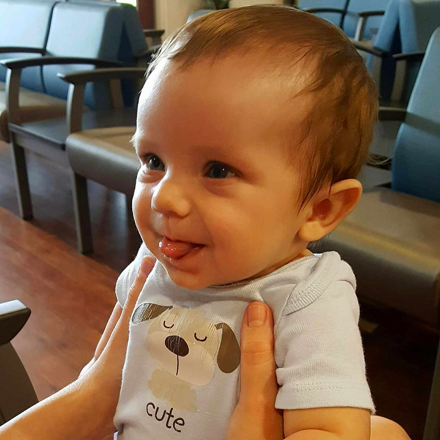 Isaac Lasserre is registered to the contest to win money with this photo: baby, casual, chairs, child, cute, expression, face, hands, holding, indoor, infant, light, onesie, person, short_sleeves, smiling, tongue_out, waiting_room, wood_floor, young