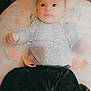 baby, infant, child, pacifier, cushion, blanket, clothing, face, portrait, lying_down, indoors, soft_texture, cute, baby_clothes, looking, expression, comfortable, home, young, skin