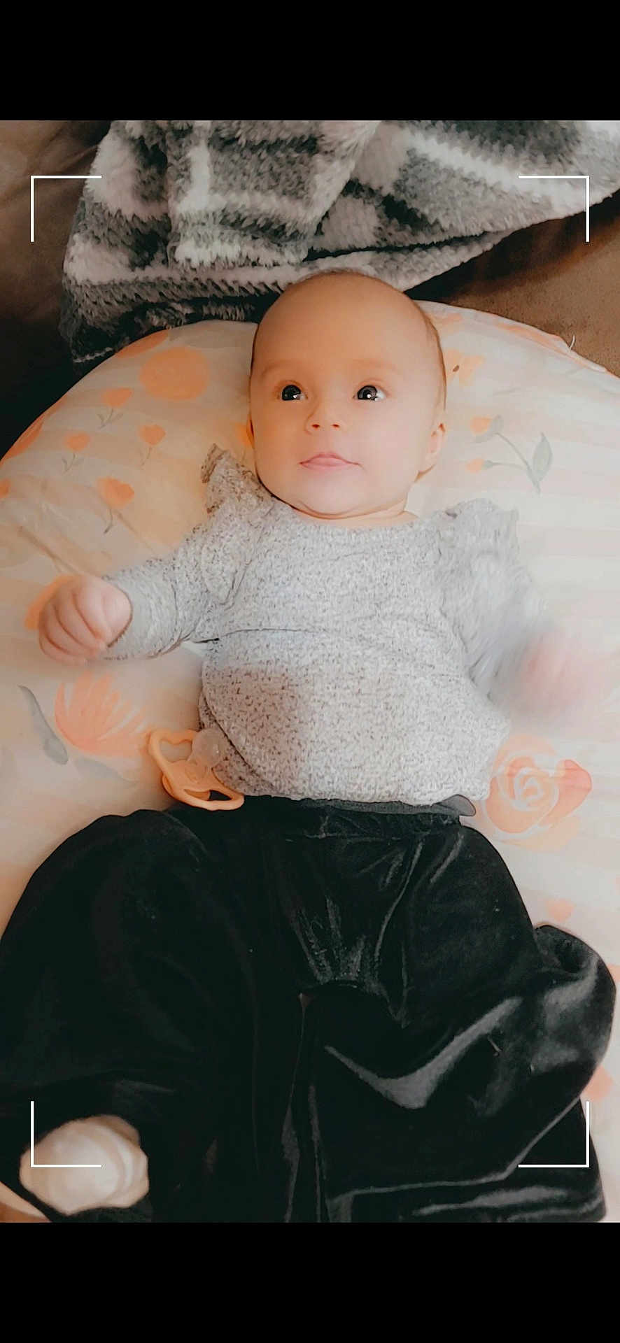 Athena is registered to the contest to win money with this photo: baby, infant, child, pacifier, cushion, blanket, clothing, face, portrait, lying_down, indoors, soft_texture, cute, baby_clothes, looking, expression, comfortable, home, young, skin