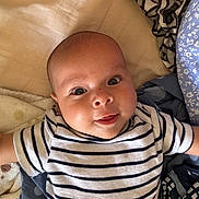 Rose participe au concours pour gagner de l'argent avec cette photo : baby, infant, striped_shirt, blanket, lying_down, smiling, cute, face, skin, head, eyes, tongue, child, happy, indoors, soft, cozy, fabric, closeup, person