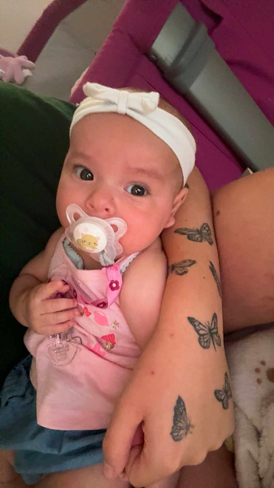 Rose a rejoint le concours — aidez-le/la à gagner de superbes lots ! baby, headband, pacifier, tattoo, butterfly_tattoo, arm, couch, pink_clothing, child, indoor, person, hand, cute, infant, sitting, holding, relaxing, skin, furniture, comfort
