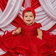 Leslie is registered to the contest to win money with this photo: baby, red_dress, headband, smiling, child, portrait, fabric, dress, seated, happy, cute, indoor, celebration, festive, tulle, lace, colorful, adorable, person, background