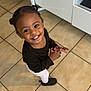 Meera a rejoint le concours — aidez-le/la à gagner de superbes lots ! child, toddler, smile, happy, indoor, kitchen, tile_floor, black_top, white_leggings, hair_buns, cute, person, standing, looking_up, shoes, earrings, young, bright_eyes, playful, casual_clothing
