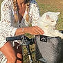 woman, cat, bicycle, basket, outdoor, grass, hat, braids, white_cat, sunlight, nature, greenery, summer, casual_clothing, smiling, pet, animal, recreation, leisure, daytime