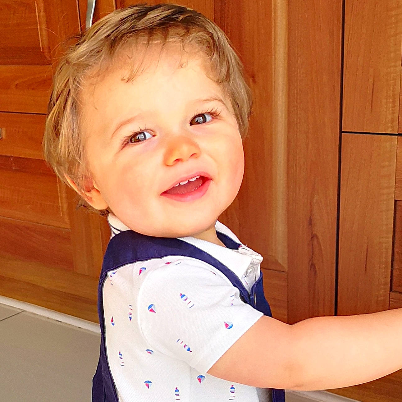 Finlay is registered to the contest to win money with this photo: baby_toddler_clothing, cheek, chin, collar, eye, eyelash, face, facial_expression, gesture, happy, iris, neck, nose, person, skin, sleeve, smile, standing, t_shirt, toddler