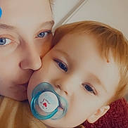 Maël participe au concours pour gagner de l'argent avec cette photo : adult, child, toddler, pacifier, kiss, face, closeup, indoor, love, affection, blue_eyes, blond_hair, yellow_clothing, blanket, cuddle, cozy, person, portrait, rest, comfort