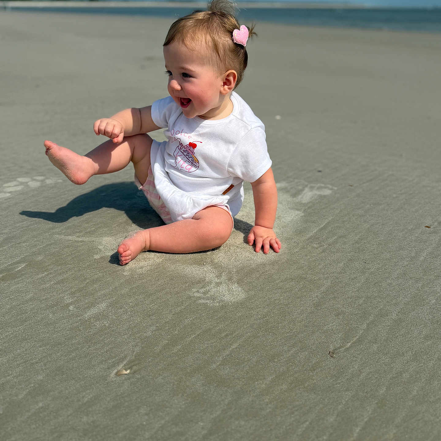 Nora is registered to the contest to win money with this photo: toddler, child, beach, sand, ocean, sky, sunny, happy, smiling, hair_clip, white_tshirt, shorts, barefoot, playing, outdoor, nature, footprints, summer, portrait, fun