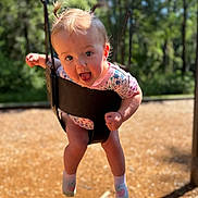 Nora is registered to the contest to win money with this photo: baby, child, swing, playground, outdoor, happy, smiling, pigtails, toddler, sunlight, nature, trees, clothing, socks, fun, excitement, face, person, play, summer