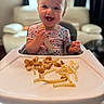 Nora joined the competition — help win amazing prizes! toddler, child, high_chair, food, fries, chicken_nuggets, smiling, happy, indoor, person, meal, eating, cute, baby, clothing, seatbelt, face, hands, table, home