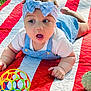 baby, blue_bow, child, curious, cute, expression, face, grass, headband, infant, outdoor, overalls, playing, quilt, red_stripes, summer, toddler, toy_ball, white_shirt, white_stripes