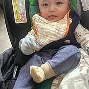 Noah is registered to the contest to win money with this photo: baby, car_seat, bib, blanket, clothing, cozy, cute, face, infant, indoors, looking, person, portrait, sitting, smile, soft, warm, wearing, young_child, young_infant
