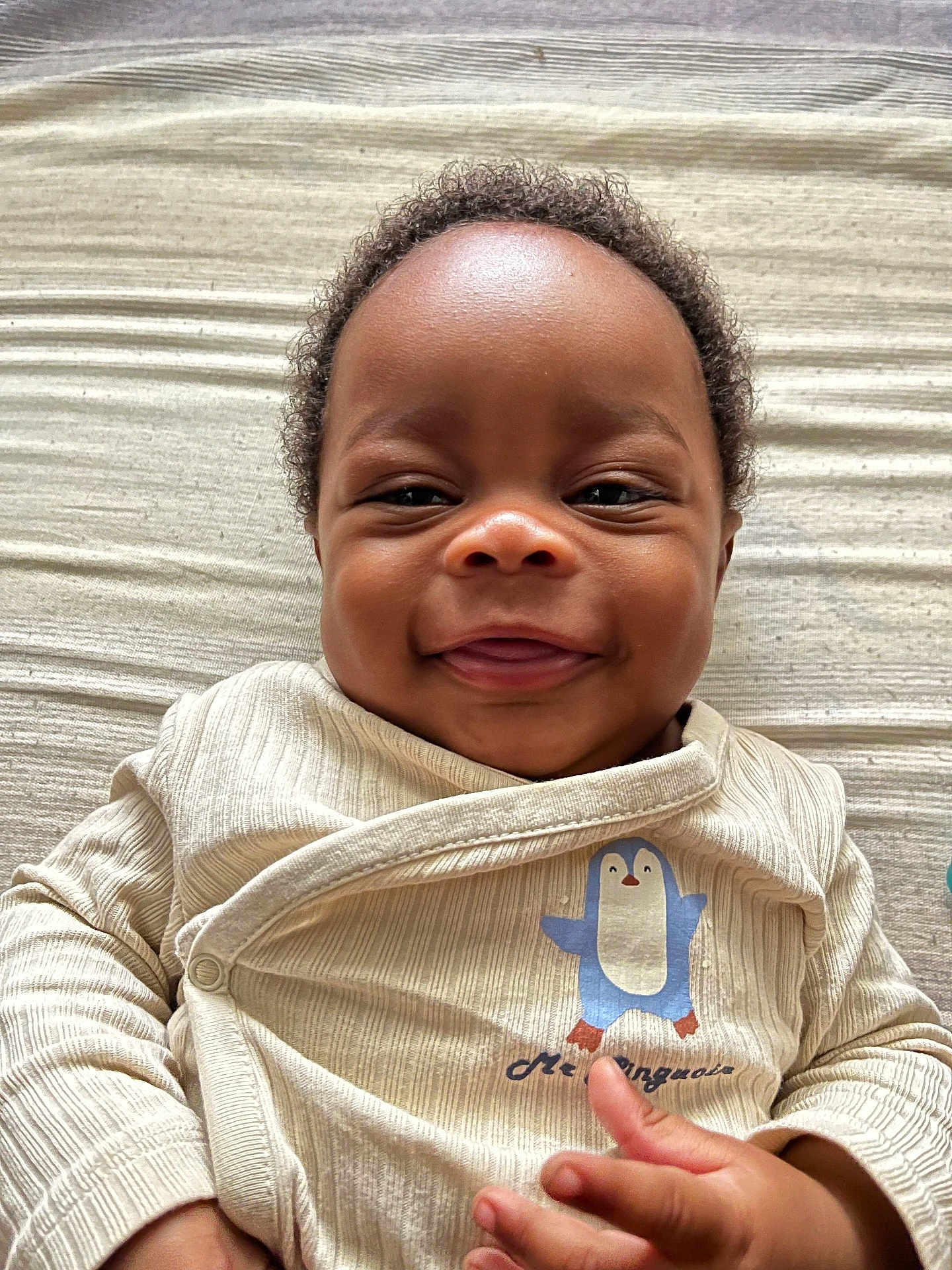 Elohim a rejoint le concours — aidez-le/la à gagner de superbes lots ! baby, smiling, infant, curly_hair, cute, penguin, clothing, light_blanket, happy, portrait, face, hand, lying_down, child, young, indoors, closeup, cheerful, apparel, fabric