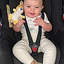baby, child, car_seat, sunglasses, plush_toy, smiling, happy, infant, clothing, shoes, seatbelt, cute, indoors, person, young_child, fashion, accessory, sitting, playful, adorable