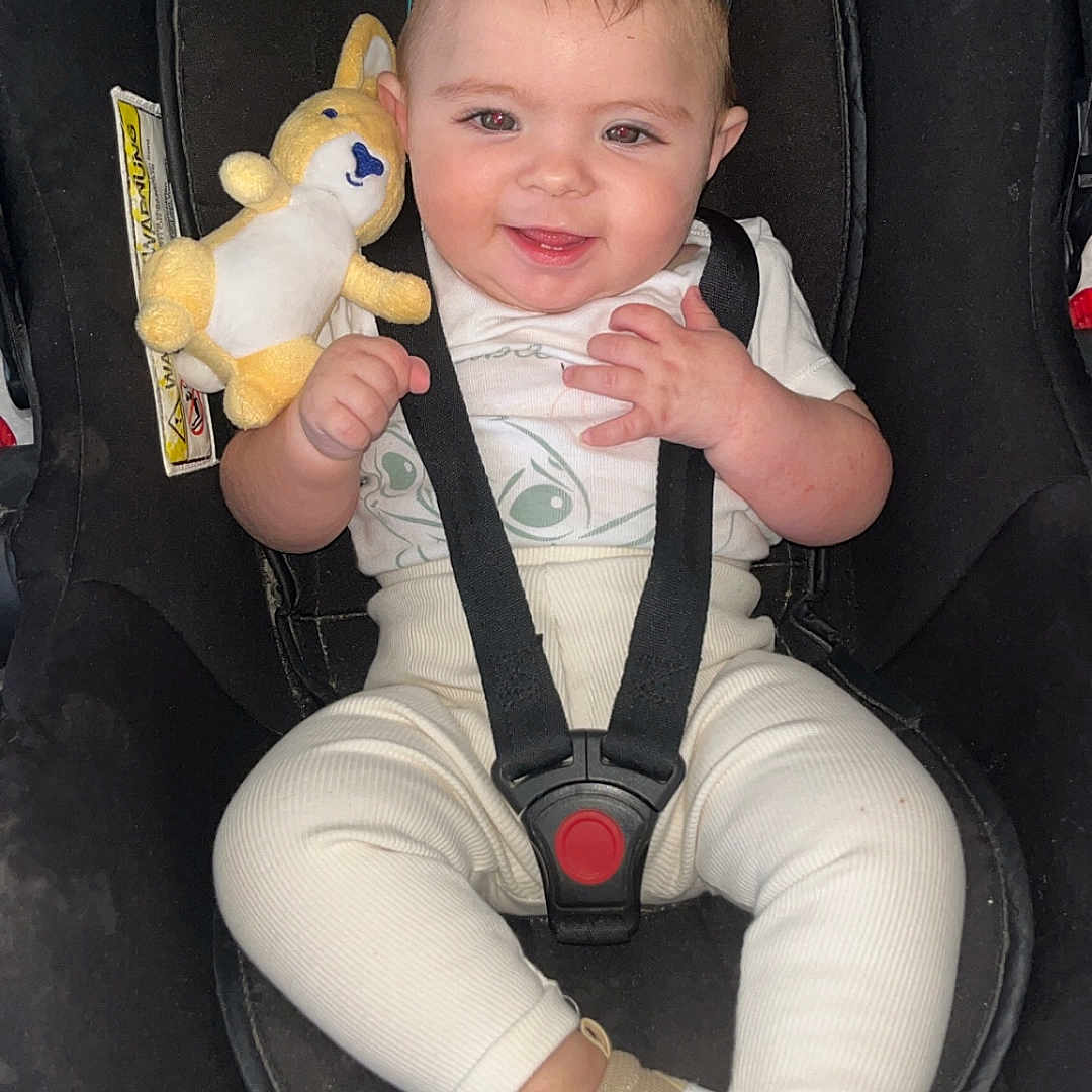 Kélyana participe au concours pour gagner de l'argent avec cette photo : accessory, adorable, baby, car_seat, child, clothing, cute, fashion, happy, indoors, infant, person, playful, plush_toy, seatbelt, shoes, sitting, smiling, sunglasses, young_child
