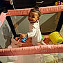 Elyana joined the competition — help win amazing prizes! toddler, child, playpen, toy, smile, indoor, baby, plush_toy, bucket, clothing, hair_tie, mesh_sides, floor, colorful, expression, standing, cute, happy, young_child, playtime