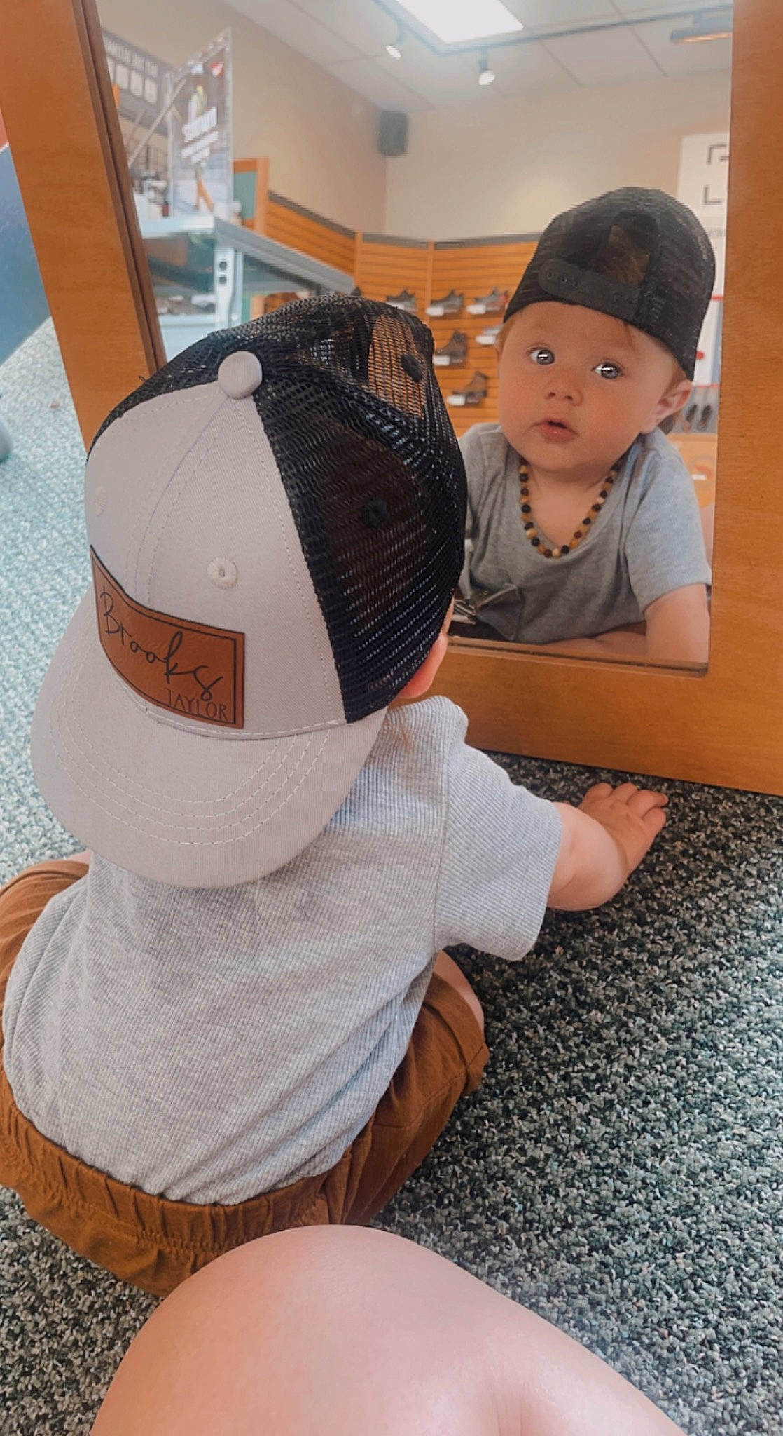 Brooks is registered to the contest to win money with this photo: baby, baby_toddler_clothing, cap, child, comfort, fashion_accessory, floor, flooring, fun, headgear, headwear, mammal, pattern, person, room, sitting, sleeve, stuffed_toy, surprise, t_shirt