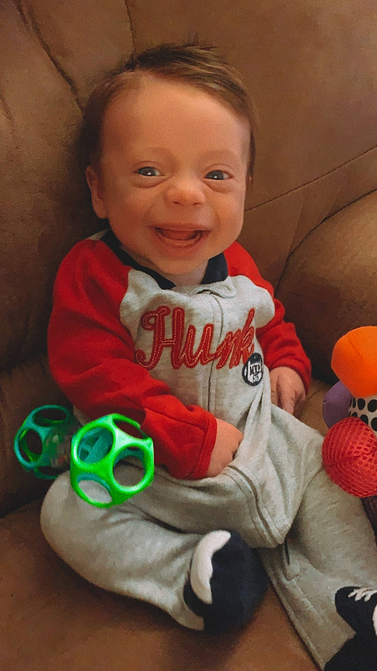 Liam is registered to the contest to win money with this photo: baby, baby_toddler_clothing, cheek, cool, eye, face, finger, hand, happy, head, human_body, iris, mouth, nose, organ, person, product, skin, sleeve, smile