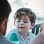 Isaac a rejoint le concours — aidez-le/la à gagner de superbes lots ! child, boy, curly_hair, white_shirt, water_bottle, face, portrait, outdoor, people, daylight, candid, smile, young, person, blurry_background, conversation, family, casual, natural_light, curiosity
