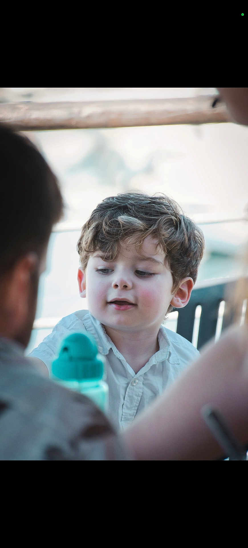 Isaac a rejoint le concours — aidez-le/la à gagner de superbes lots ! child, boy, curly_hair, white_shirt, water_bottle, face, portrait, outdoor, people, daylight, candid, smile, young, person, blurry_background, conversation, family, casual, natural_light, curiosity