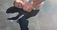 Izzahbella is registered to the contest to win money with this photo: baby, barefoot, child, diaper, face, feet, hands, happy, infant, lying_down, outdoor, photography, playful, portrait, recreation, shadow, smiling, summer, sunlight, trampoline