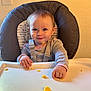 Emily is registered to the contest to win money with this photo: baby, child, high_chair, food, crumbs, smile, face, clothing, indoor, person, table, feeding, seat, cute, happy, young_child, hair, hand, wall, frame