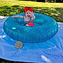 Emily is registered to the contest to win money with this photo: baby, child, red_bow, blue_inflatable_ring, blanket, grass, outdoor, smiling, waving, sunlight, happy, summer, candid, cute, playful, headwear, infant, portrait, nature, daytime