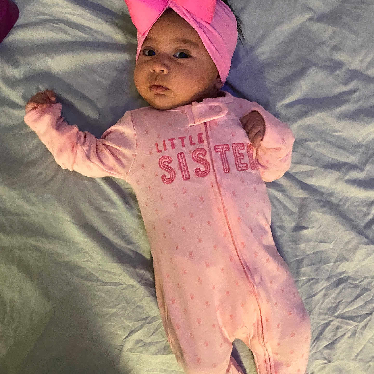 Yamileth is registered to the contest to win money with this photo: baby, bed, blanket, bow, child, cute, face, headband, indoors, infant, lying_down, onesie, person, pink, portrait, sleeping_area, sleepwear, soft_lighting, text_on_clothing, young