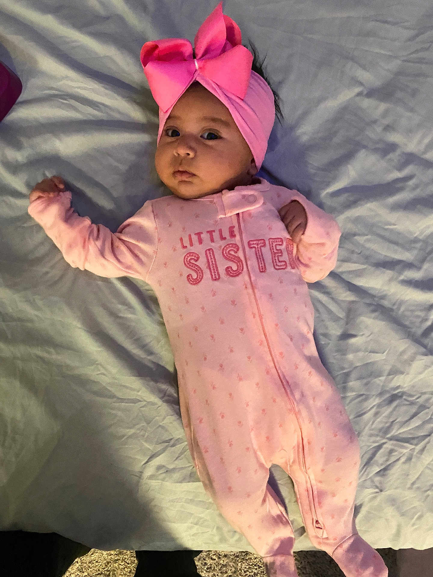 Yamileth is registered to the contest to win money with this photo: baby, infant, pink, onesie, headband, bow, sleepwear, bed, lying_down, child, face, person, cute, young, indoors, text_on_clothing, soft_lighting, blanket, sleeping_area, portrait