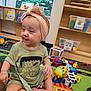 Charlotte Mae joined the competition — help win amazing prizes! toddler, child, headband, toy, playmat, indoor, sitting, shirt, green, smile, baby, floor, colorful, playroom, furniture, window, bookshelf, vehicle_toy, plastic_toy, expression