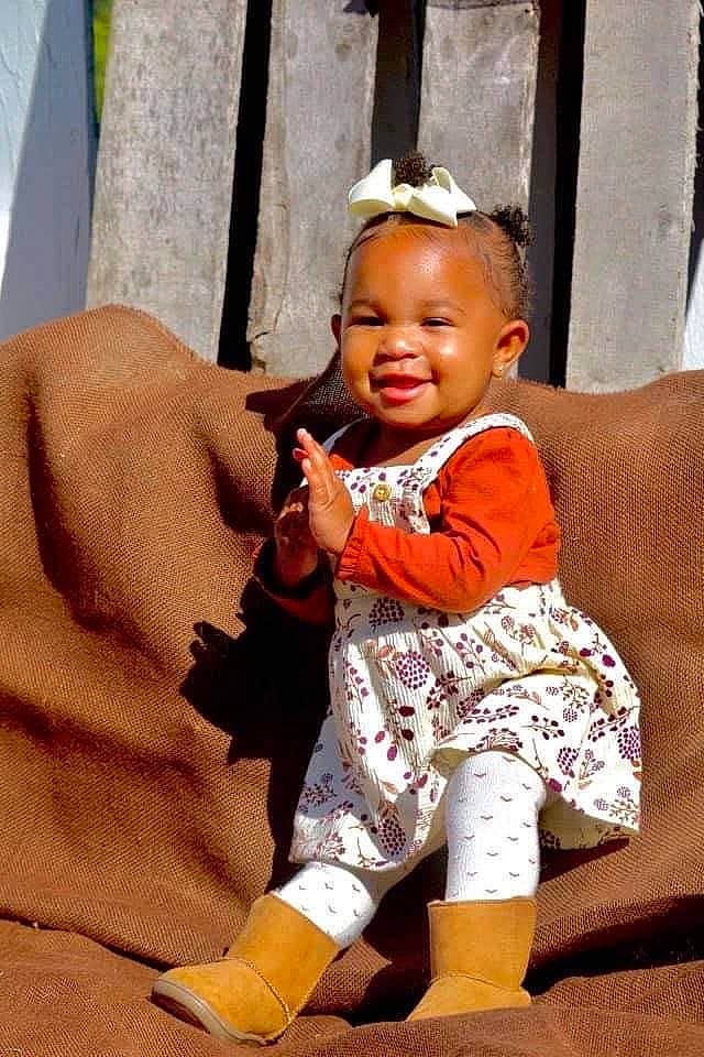 Alaiyah is registered to the contest to win money with this photo: baby, baby_laughing, baby_toddler_clothing, child, child_model, couch, curtain, hair_accessory, headband, headpiece, joy, living_room, person, sock, toddler