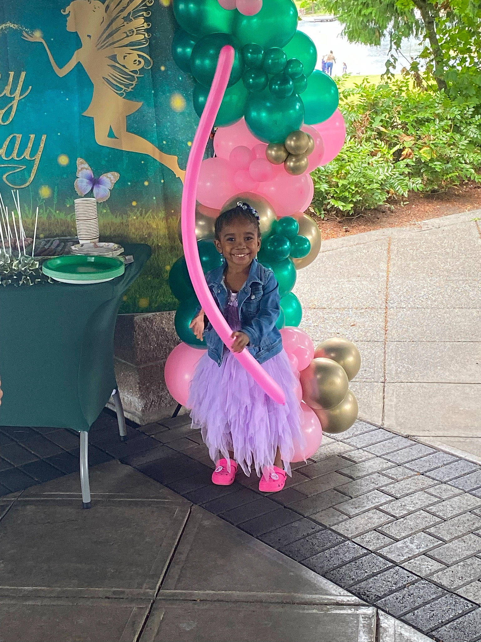 Aziyah is registered to the contest to win money with this photo: art, balloon, costume, electric_blue, entertainment, event, flooring, fun, grass, joy, leisure, magenta, party, party_supply, person, pink, plant, purple, sitting, tree