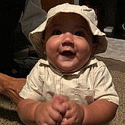 Niko is registered to the contest to win money with this photo: baby, child, hat, bucket_hat, clothing, carpet, indoor, smiling, happy, portrait, hands, person, floor, furniture, home, cabinet, photography, face, sitting, cute