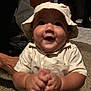 baby, child, hat, bucket_hat, clothing, carpet, indoor, smiling, happy, portrait, hands, person, floor, furniture, home, cabinet, photography, face, sitting, cute