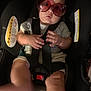 baby, car_seat, sunglasses, child, seatbelt, hands, legs, warning_label, car_interior, infant, clothing, cute, sitting, portrait, baby_face, young_child, child_safety, seat_harness, indoor, closeup