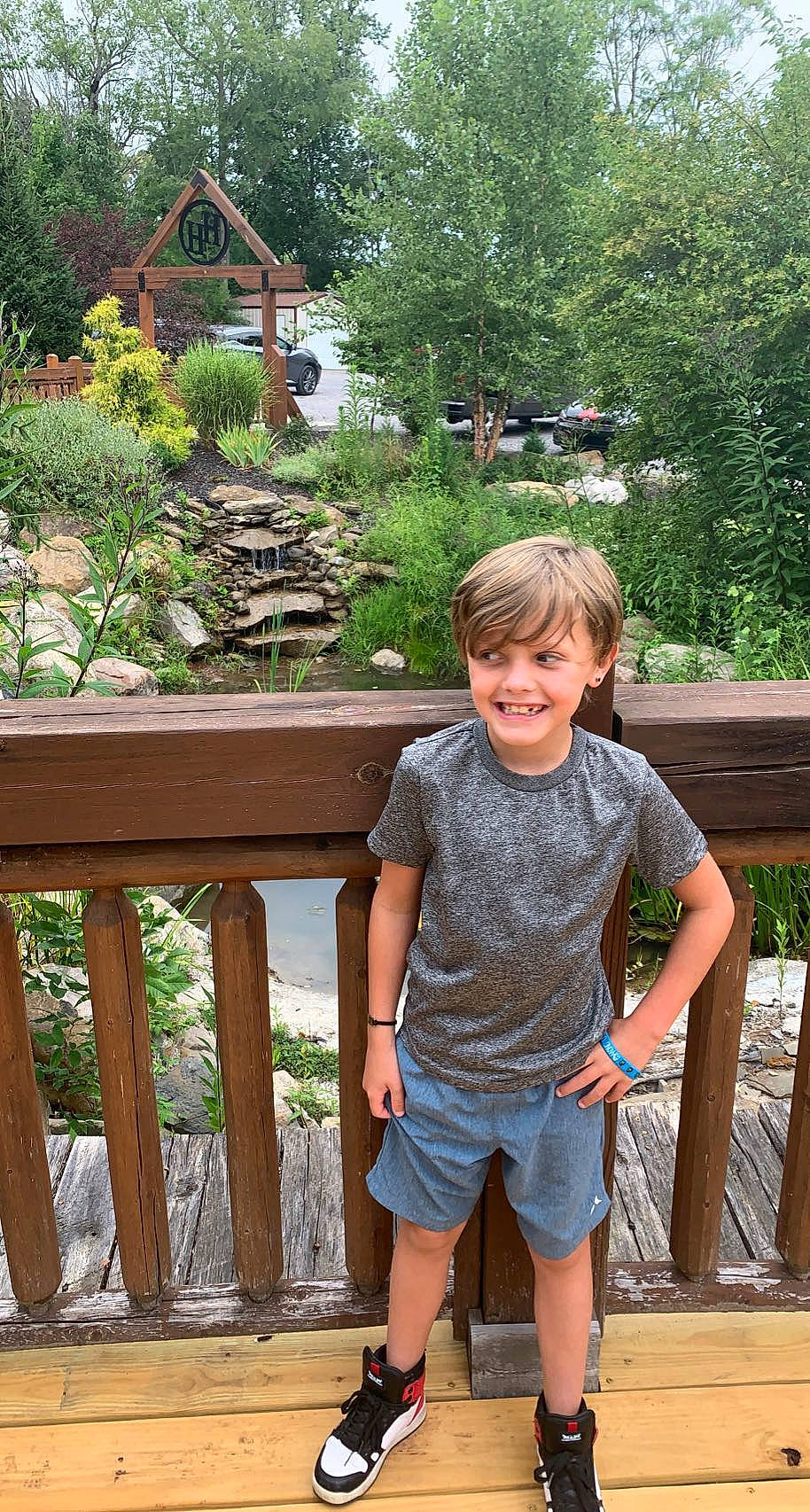 Kanen is registered to the contest to win money with this photo: fence, fun, grass, happy, joy, landscape, leaf, leisure, mammal, nature, people, person, plant, public_space, shorts, smile, summer, toddler, travel, tree