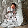 baby, newborn, infant, baby_rocker, carpet, indoor, sleeping, clothing, onesie, straps, face, hair, comfort, soft, pattern, wood_panel, baby_toys, vibration_control, resting, peaceful