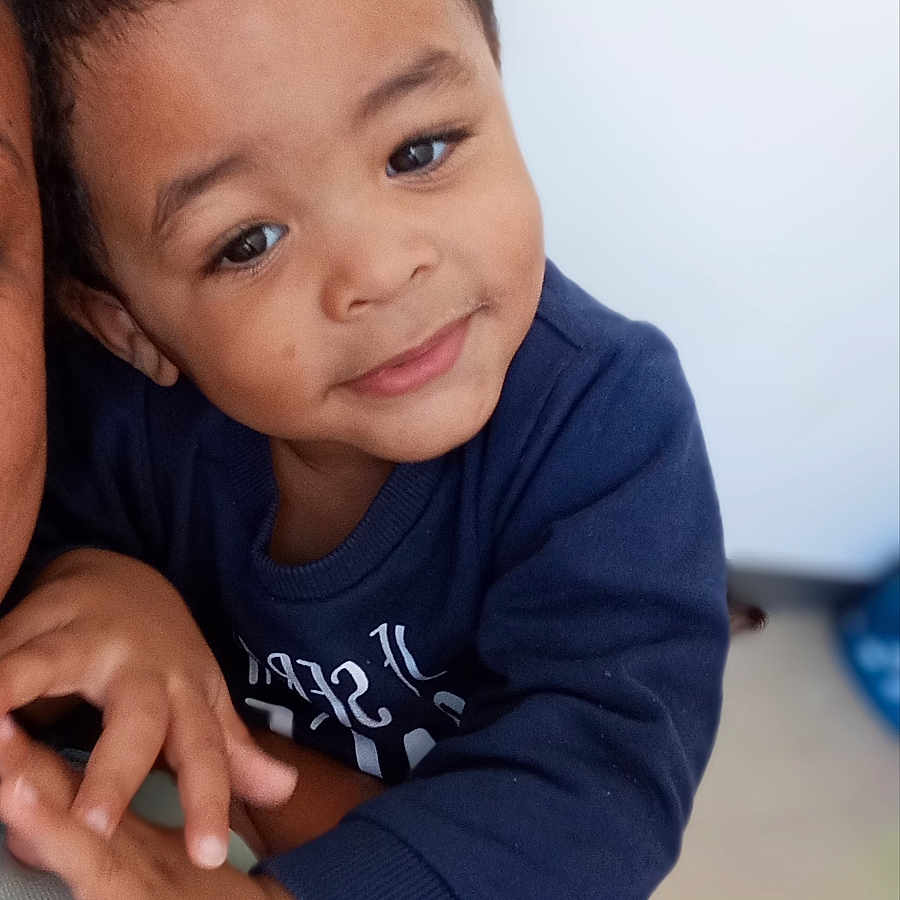 Owen participe au concours pour gagner de l'argent avec cette photo : affection, arm, baby, blue_sweatshirt, child, closeup, clothing, curly_hair, cute, face, hand, happy, indoor, person, portrait, skin, smile, toddler, warmth, young_child