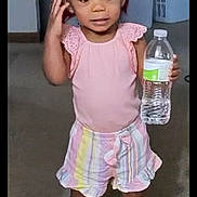 Ka'Lani joined the competition — help win amazing prizes! toddler, child, indoors, standing, pink_clothing, striped_shorts, water_bottle, carpet, laundry_basket, household, footwear, shoes, person, young_child, hair_buns, casual, smiling, room, home, cute