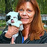 Maddie is registered to the contest to win money with this photo: animal, casual, cute, dog, face, fence, greenery, happy, holding, jacket, nature, outdoor, person, pet, portrait, puppy, smiling, tongue, tree, woman