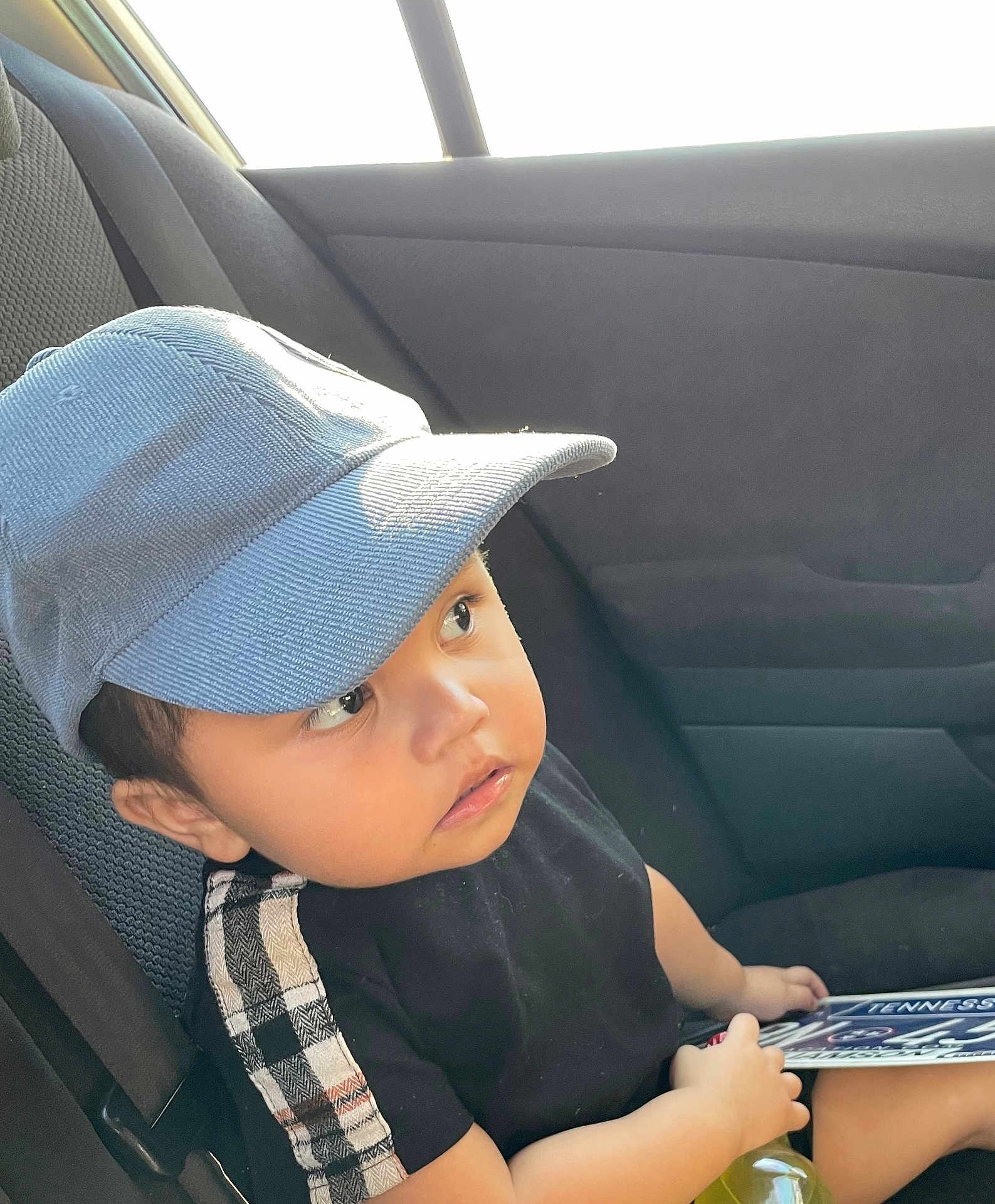 Henry joined the competition — help win amazing prizes! toddler, child, cap, car_seat, car_interior, license_plate, black_shirt, plaid, seatbelt, window, sunlight, curious, face, hand, young_child, portrait, casual_clothing, sitting, vehicle, daylight