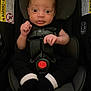 baby, infant, car_seat, black_clothing, safety_harness, wide_eyes, indoor, seat, child, cute, small_hands, footwear, expression, headrest, straps, warning_labels, newborn, portrait, human, young
