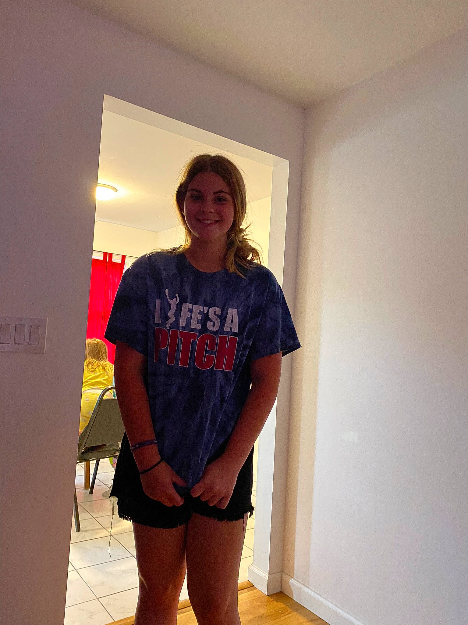 Alexia is registered to the contest to win money with this photo: abdomen, active_shirt, elbow, electric_blue, fashion_design, flooring, fun, human_leg, joy, knee, long_hair, magenta, neck, person, room, sleeve, smile, sportswear, t_shirt, thigh