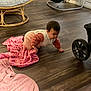 baby, crawling, blanket, wood_floor, indoor, furniture, baby_gear, chair, baby_bouncer, pink, cozy, child, person, flooring, home, infant, clothing, toy, living_room, wheel