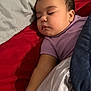Kaylani is registered to the contest to win money with this photo: baby, sleeping, blanket, pillow, bed, purple_shirt, earring, infant, closeup, rest, peaceful, indoor, soft_lighting, cute, child, portrait, hand, skin, comfort, relaxation