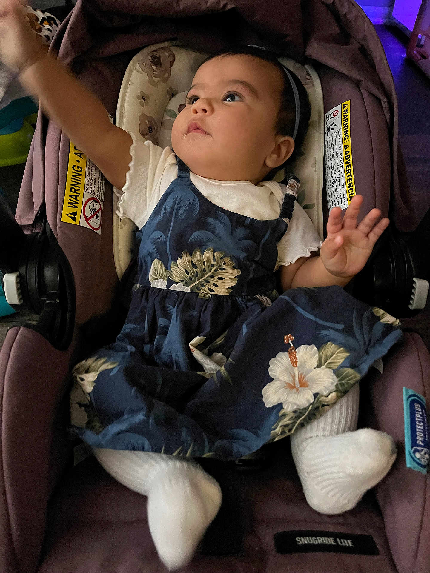Kaylani joined the competition — help win amazing prizes! baby, child, car_seat, dress, white_socks, indoor, infant, seat, clothing, person, headband, expression, drool, comfort, seatbelt, fabric, toy, floor, footwear, cute