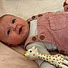 baby, buttons, cheeks, closeup, clothing, corduroy, cute, eyes, face, hand, infant, lying_down, nursery, pink_overalls, plush_blanket, portrait, rubber_toy, smile, soft_texture, toy_giraffe