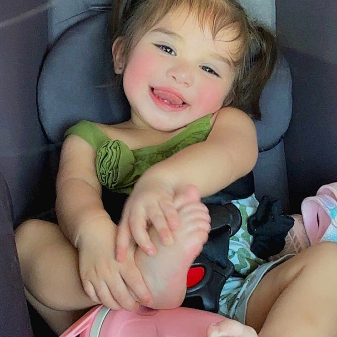 Alaina is registered to the contest to win money with this photo: accessories, baby, bodypart, clothing, cup, cushion, dress, face, finger, furniture, hand, head, homedecor, person, photography, portrait, shorts, sitting, t_shirt, transportation