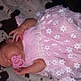 baby, sleeping, pacifier, pink_dress, floral_pattern, blanket, infant, cute, peaceful, child, rest, soft_texture, newborn, toddler, hand, face, lying_down, adorable, young, indoors