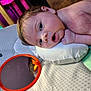 baby, infant, pillow, mirror, reflection, orange_rim, soft_surface, curious, face, head, hand, skin, child, indoor, lighting, colorful_background, closeup, expression, young, resting